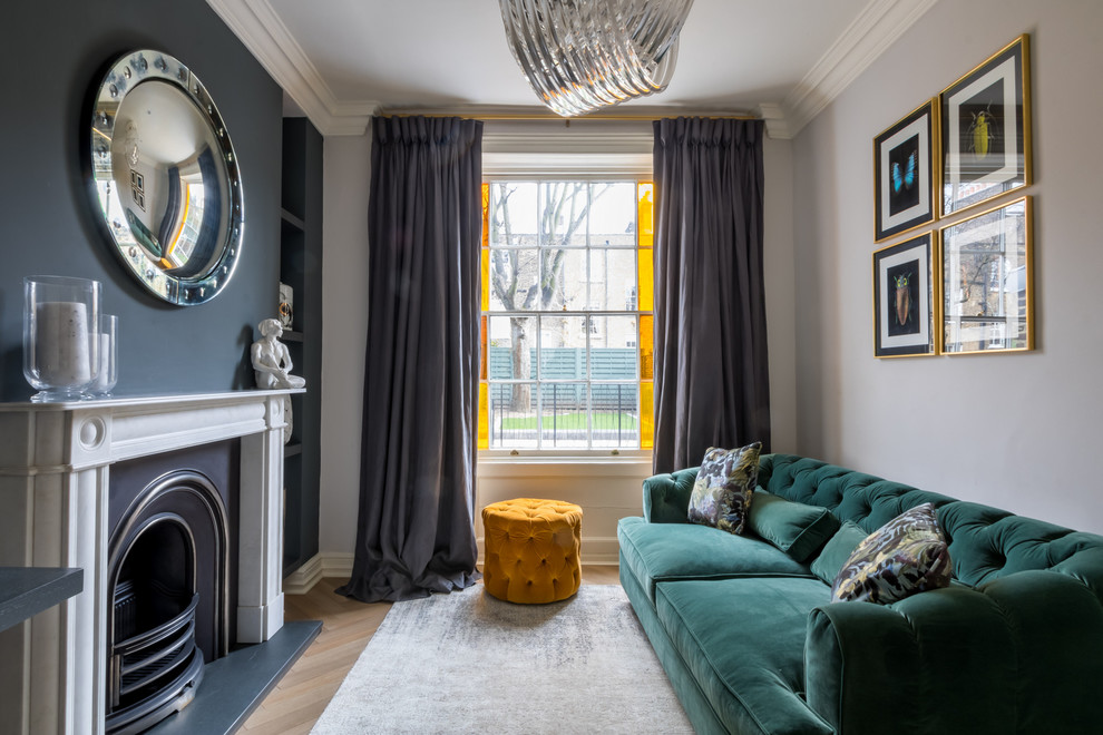 Eclectic living room in London with grey walls, a standard fireplace, light hardwood floors and no tv.