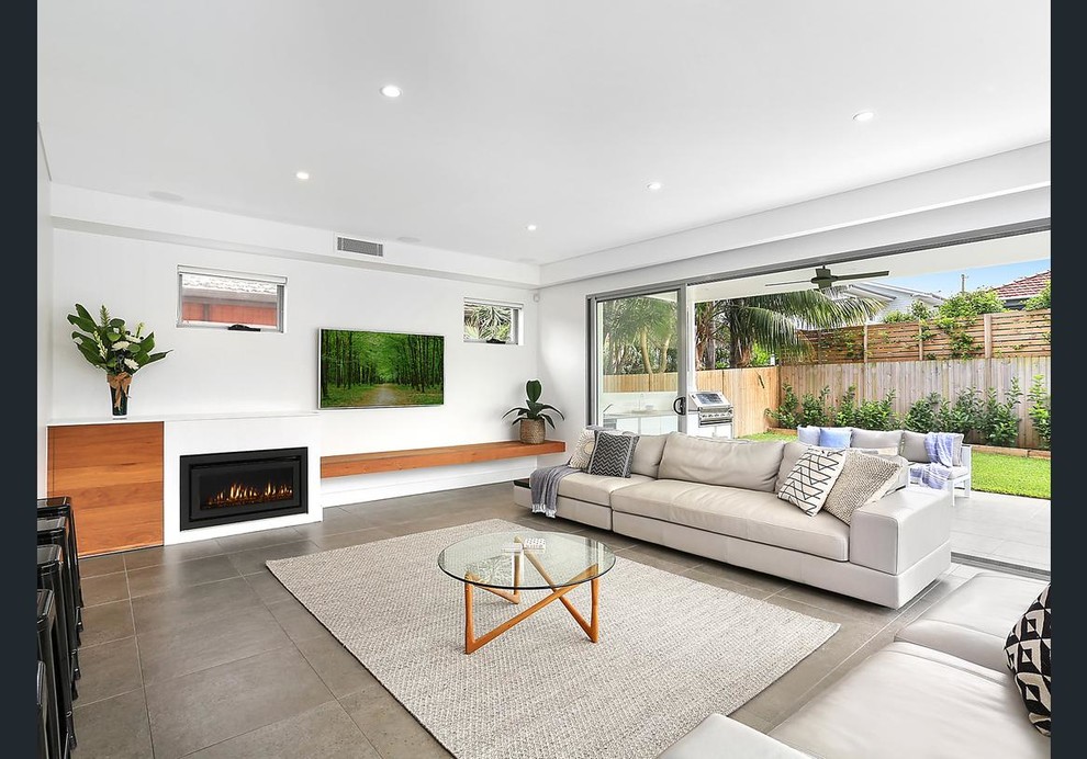 This is an example of a beach style open concept living room in Sydney with white walls and a wall-mounted tv.