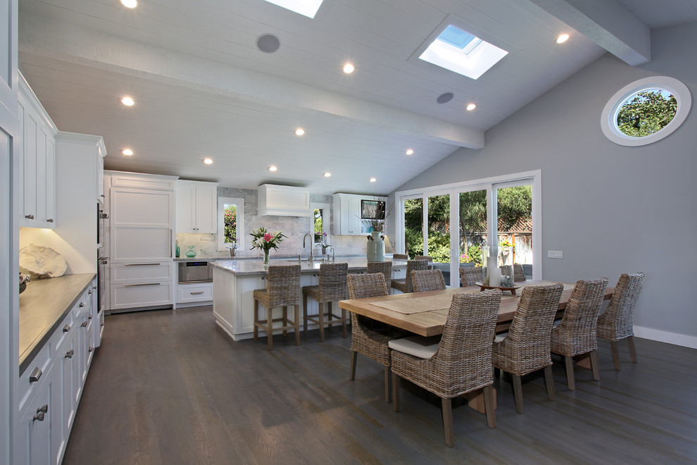 Photo of a large beach style kitchen/dining combo in Orange County with dark hardwood floors, a standard fireplace, a tile fireplace surround, grey walls and brown floor.