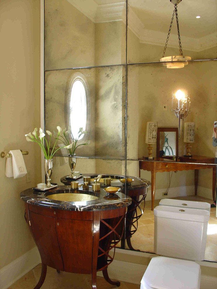 Photo of a small midcentury powder room in Los Angeles with an undermount sink, furniture-like cabinets, medium wood cabinets, onyx benchtops, a one-piece toilet, beige tile, beige walls, limestone floors and mirror tile.