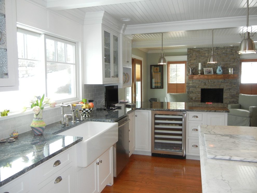 Example of a large transitional u-shaped medium tone wood floor, brown floor and shiplap ceiling open concept kitchen design with a farmhouse sink, shaker cabinets, white cabinets, granite countertops, subway tile backsplash, an island, stainless steel appliances, white backsplash and gray countertops