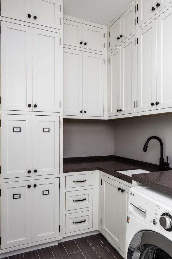 Design ideas for a mid-sized transitional l-shaped dedicated laundry room in San Francisco with an undermount sink, shaker cabinets, white cabinets, grey walls, a side-by-side washer and dryer and black benchtop.