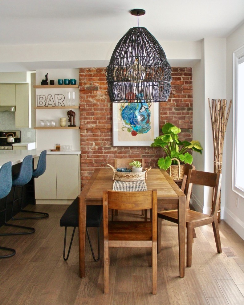 This is an example of a mid-sized tropical dining room in Toronto with white walls, medium hardwood floors, brown floor and no fireplace.