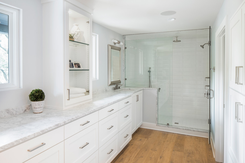 This is an example of a mid-sized eclectic master bathroom in Austin with shaker cabinets, white cabinets, marble benchtops, an alcove shower, white tile, grey walls and light hardwood floors.