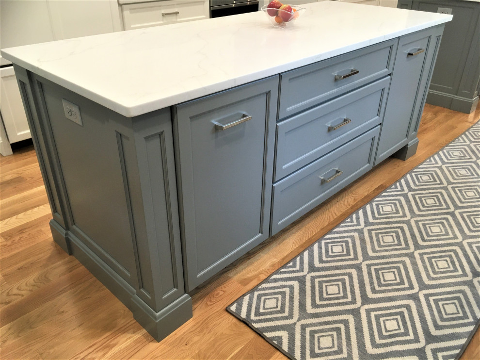 Inspiration for a large transitional galley light wood floor and brown floor eat-in kitchen remodel in Boston with an undermount sink, shaker cabinets, white cabinets, quartz countertops, white backsplash, subway tile backsplash, stainless steel appliances, two islands and white countertops