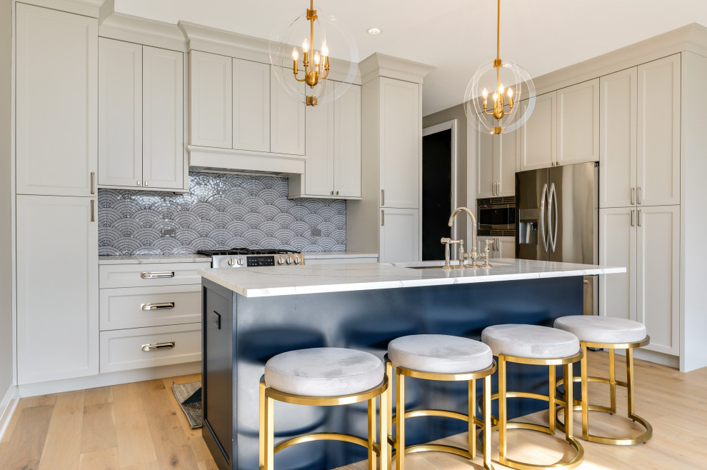 Open concept kitchen - transitional l-shaped light wood floor and beige floor open concept kitchen idea in Chicago with an undermount sink, shaker cabinets, white cabinets, gray backsplash, mosaic tile backsplash, stainless steel appliances, an island and multicolored countertops