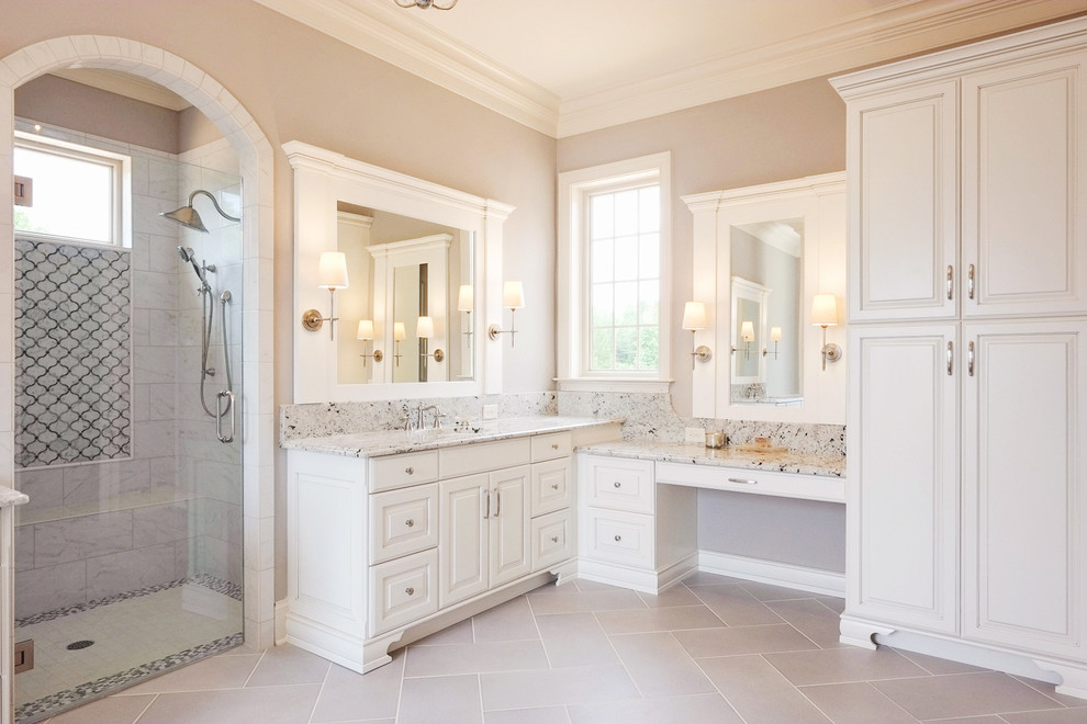 This is an example of a traditional bathroom in Charlotte with raised-panel cabinets, white cabinets, an alcove shower, gray tile, white tile, grey walls and a hinged shower door.