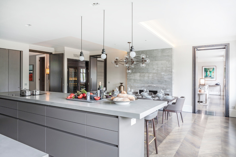 This is an example of a contemporary eat-in kitchen in London with flat-panel cabinets, grey cabinets, medium hardwood floors and with island.