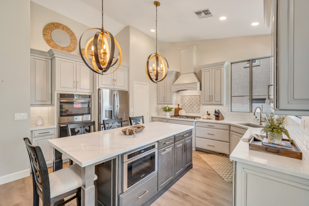 Eat-in kitchen - mid-sized transitional u-shaped eat-in kitchen idea in Phoenix with an undermount sink, raised-panel cabinets, gray cabinets, quartz countertops, white backsplash, subway tile backsplash, stainless steel appliances, an island and white countertops