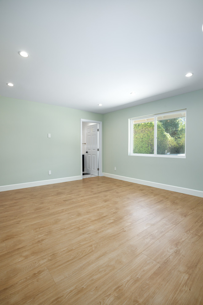 Design ideas for a mid-sized transitional master bedroom in Los Angeles with green walls, laminate floors and brown floor.