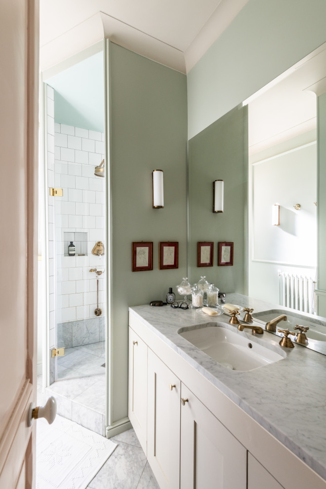 Свежая идея для дизайна: узкая и длинная ванная комната в стиле ретро с фасадами с утопленной филенкой, бежевыми фасадами, угловым душем, инсталляцией, зеркальной плиткой, зелеными стенами, мраморным полом, душевой кабиной, консольной раковиной, мраморной столешницей, белым полом, душем с распашными дверями, бежевой столешницей, тумбой под одну раковину, напольной тумбой и панелями на стенах - отличное фото интерьера