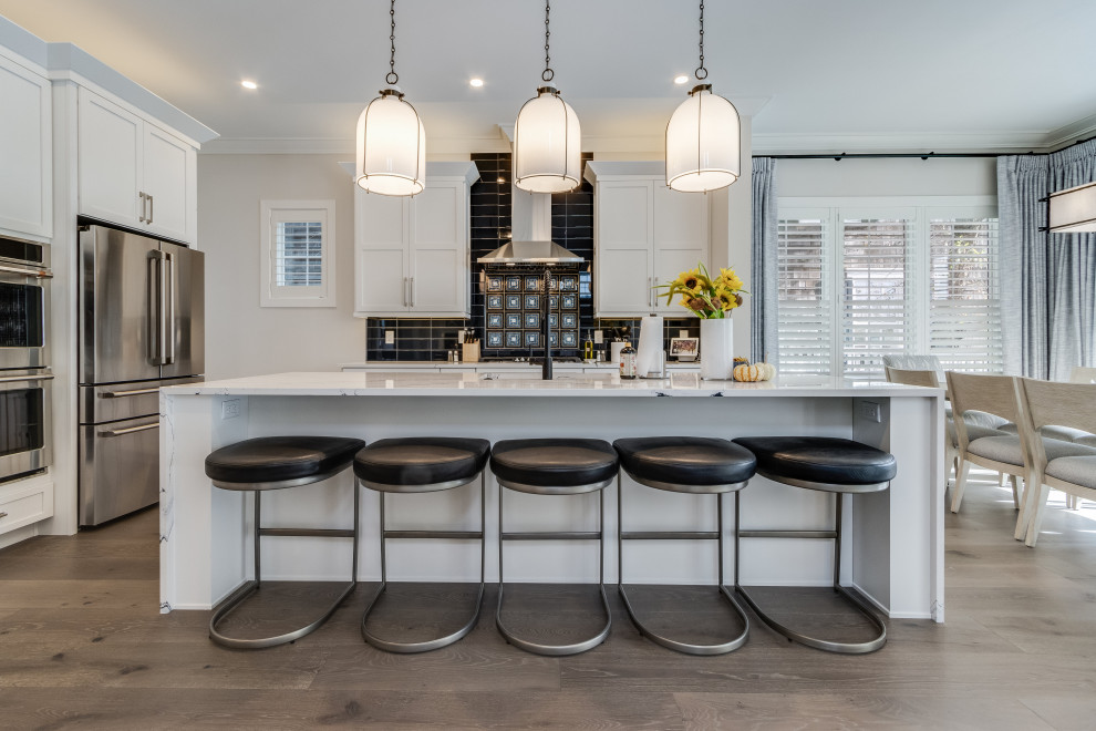 Inspiration for a mid-sized coastal light wood floor eat-in kitchen remodel with a drop-in sink, white cabinets, wood countertops, blue backsplash, stainless steel appliances, an island and white countertops