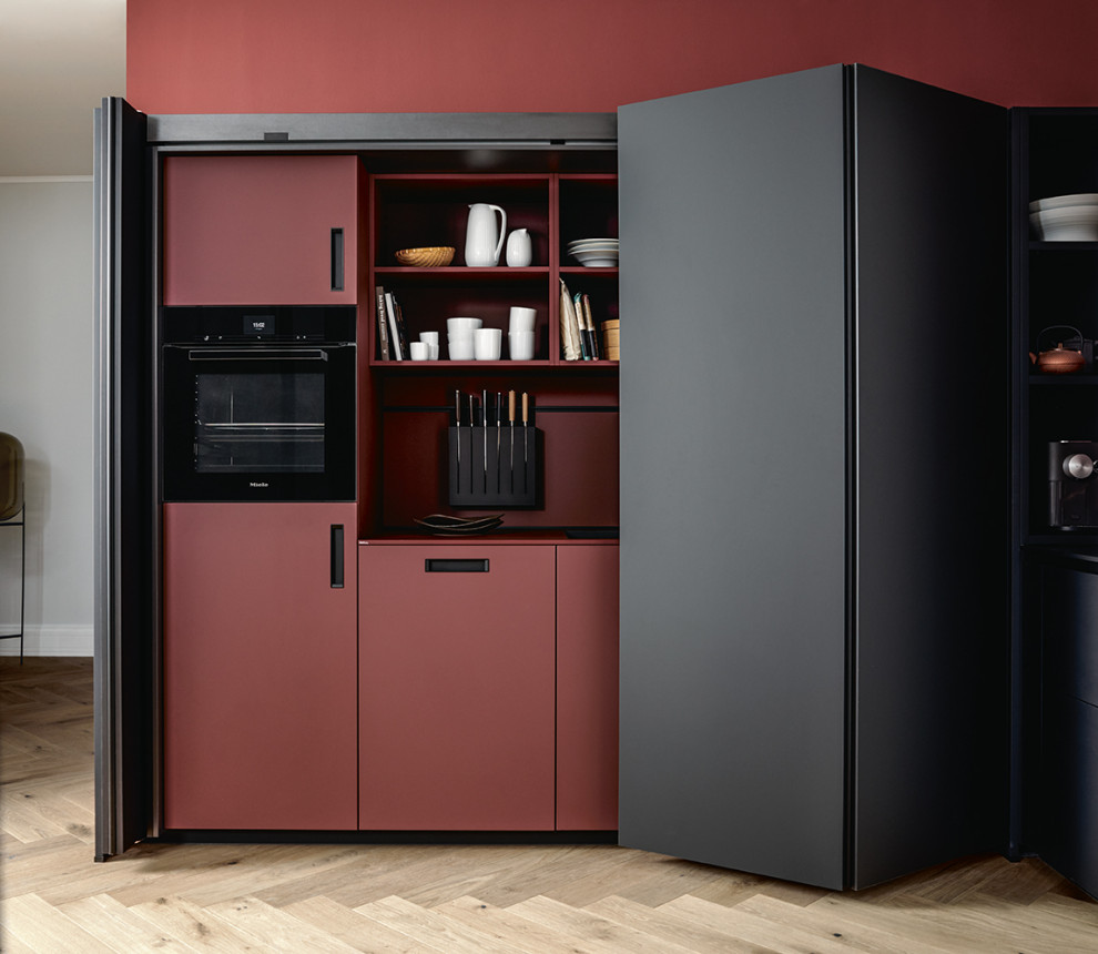Inspiration for a large asian l-shaped open plan kitchen in Nuremberg with flat-panel cabinets, black cabinets, red splashback, black appliances, with island and white benchtop.