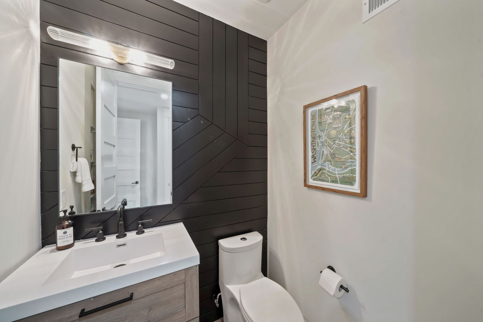 Design ideas for a mid-sized contemporary powder room in DC Metro with shaker cabinets, light wood cabinets, a one-piece toilet, an undermount sink, solid surface benchtops, white benchtops, a built-in vanity and panelled walls.