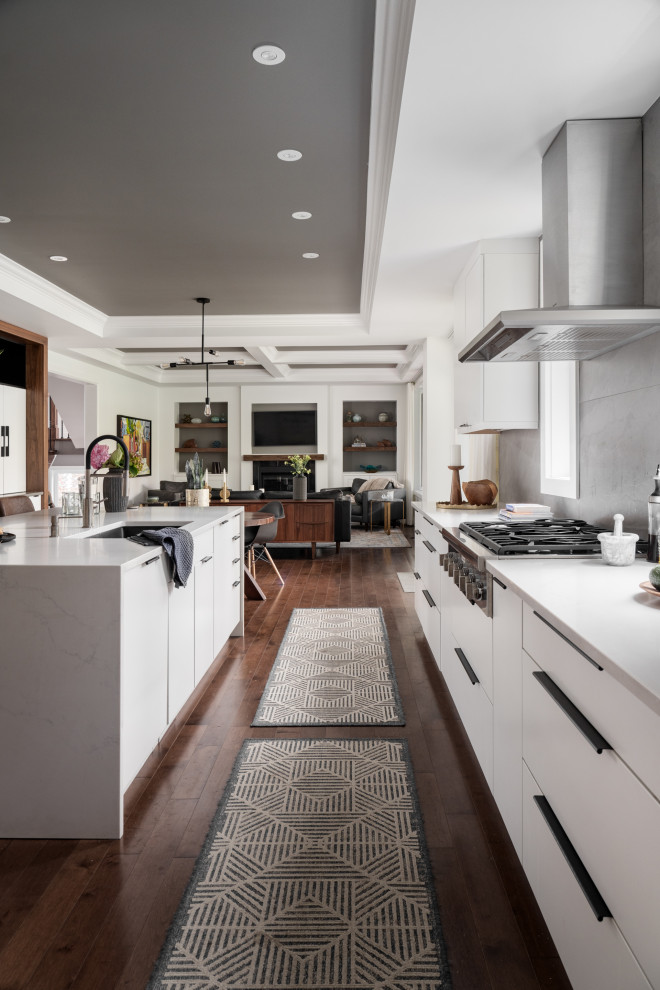Design ideas for a large transitional u-shaped eat-in kitchen in Montreal with an undermount sink, flat-panel cabinets, white cabinets, quartz benchtops, grey splashback, slate splashback, stainless steel appliances, dark hardwood floors, with island, brown floor, white benchtop and coffered.