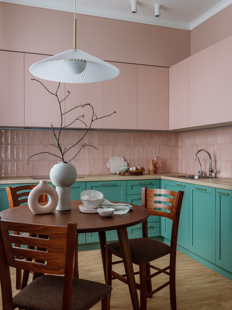 На фото: угловая кухня-гостиная среднего размера в стиле ретро с накладной мойкой, зелеными фасадами, розовым фартуком, фартуком из керамической плитки и черной техникой без острова с