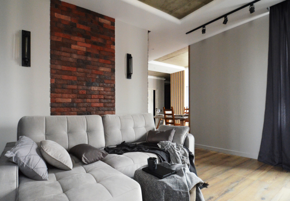 Стильный дизайн: маленькая объединенная гостиная комната в современном стиле с коричневыми стенами, полом из ламината, горизонтальным камином, фасадом камина из кирпича, телевизором на стене, зоной отдыха, коричневым полом и кирпичными стенами для на участке и в саду - последний тренд