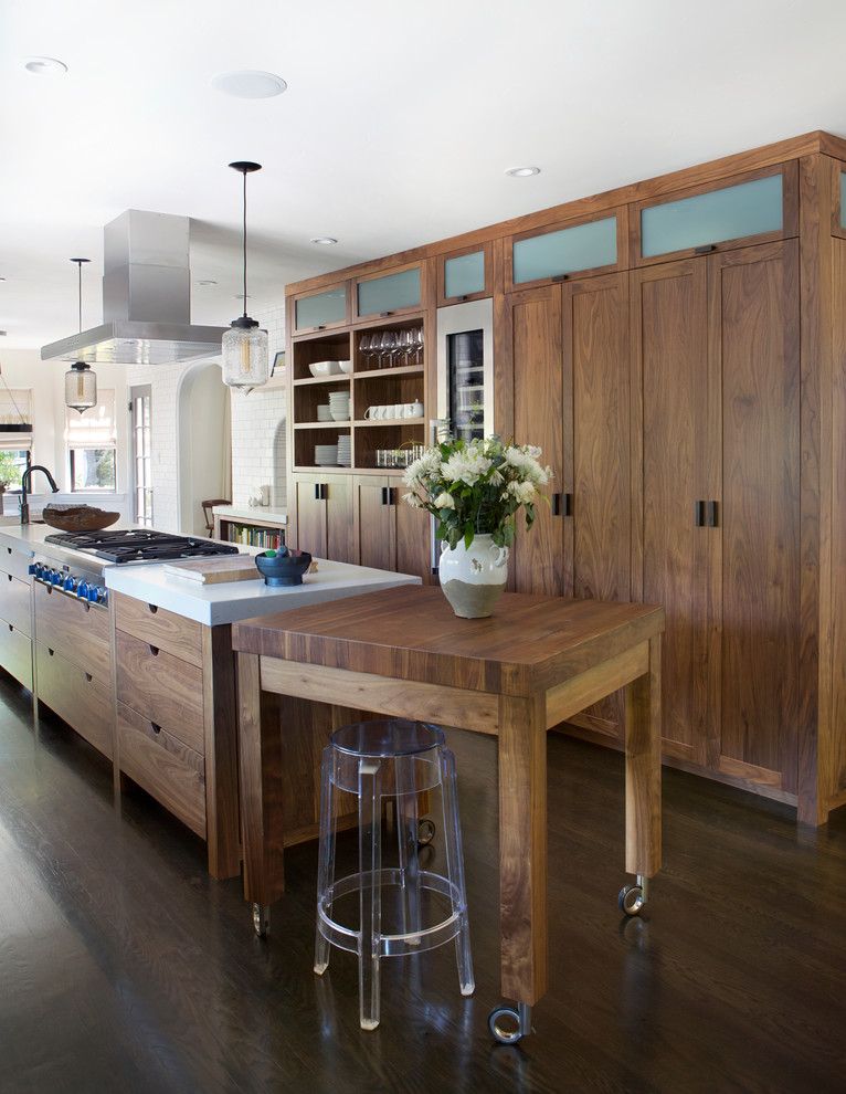 Design ideas for a mid-sized industrial galley open plan kitchen in San Francisco with flat-panel cabinets, medium wood cabinets, stainless steel appliances, dark hardwood floors, with island, an undermount sink, quartz benchtops, white splashback, subway tile splashback and brown floor.