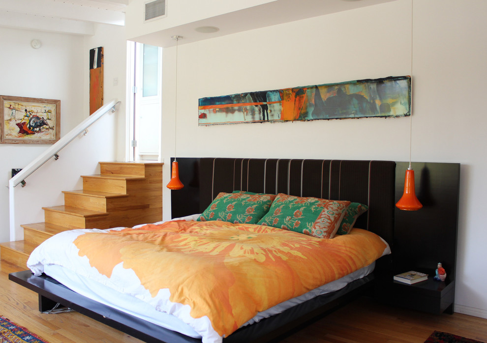 Contemporary bedroom in Los Angeles with white walls and medium hardwood floors.