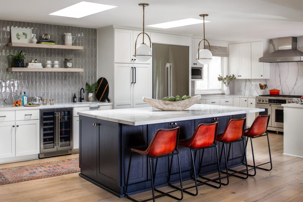 Expansive modern l-shaped kitchen/diner in San Francisco with a submerged sink, recessed-panel cabinets, white cabinets, quartz worktops, grey splashback, metro tiled splashback, stainless steel appliances, light hardwood flooring, an island, brown floors and multicoloured worktops.