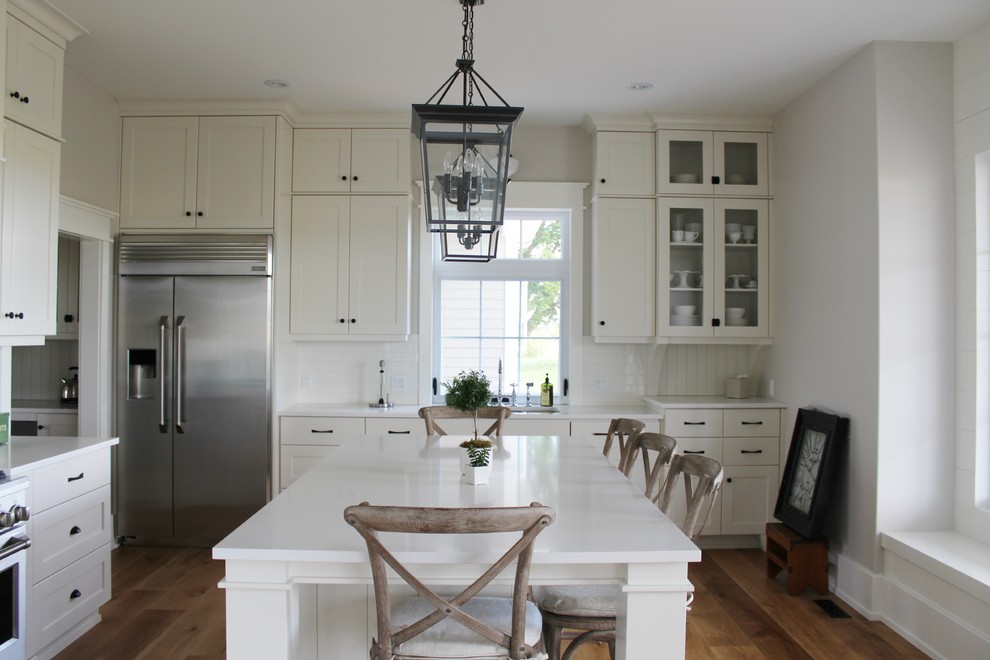 Eat-in kitchen - large transitional l-shaped eat-in kitchen idea in Toronto with an undermount sink, shaker cabinets, white cabinets, quartz countertops, white backsplash, stainless steel appliances and an island