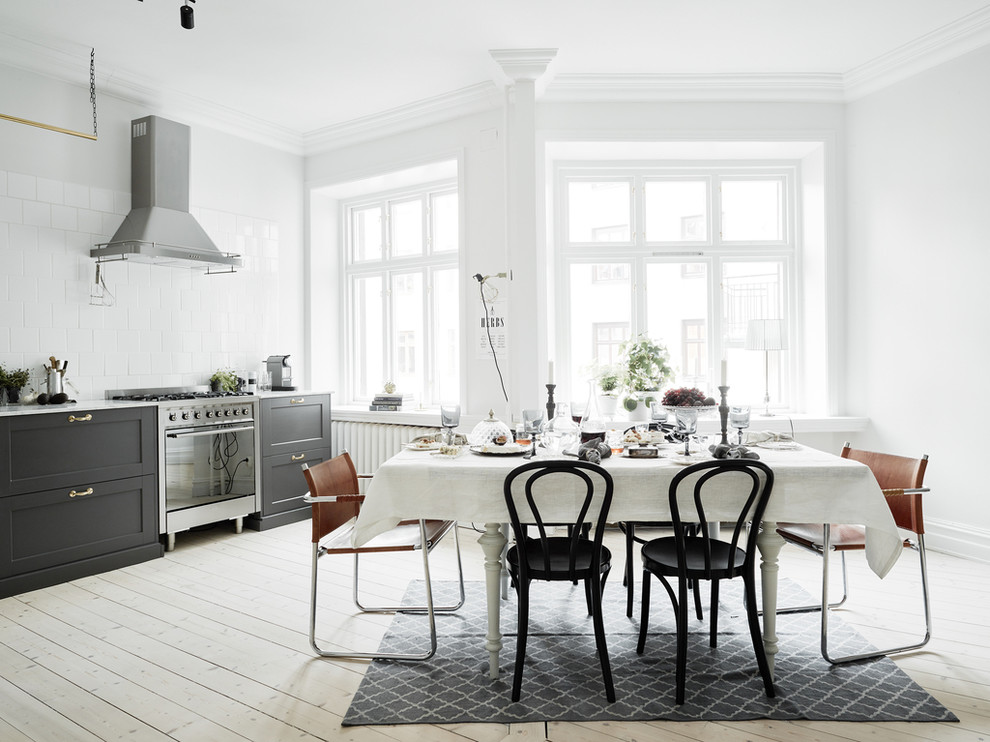 Design ideas for a mid-sized contemporary kitchen/dining combo in Gothenburg with white walls, light hardwood floors and no fireplace.