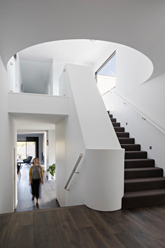 Inspiration for a large contemporary carpeted u-shaped staircase in Melbourne with carpet risers and wood railing.