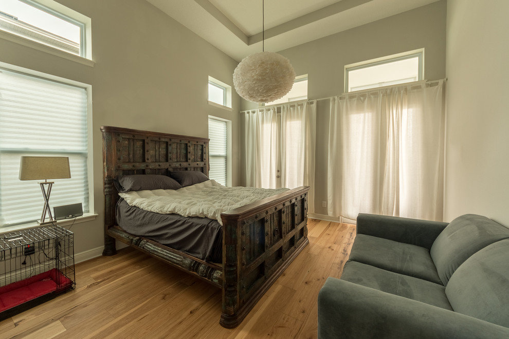 Photo of a large contemporary master bedroom in Orlando with light hardwood floors, white walls, no fireplace and beige floor.