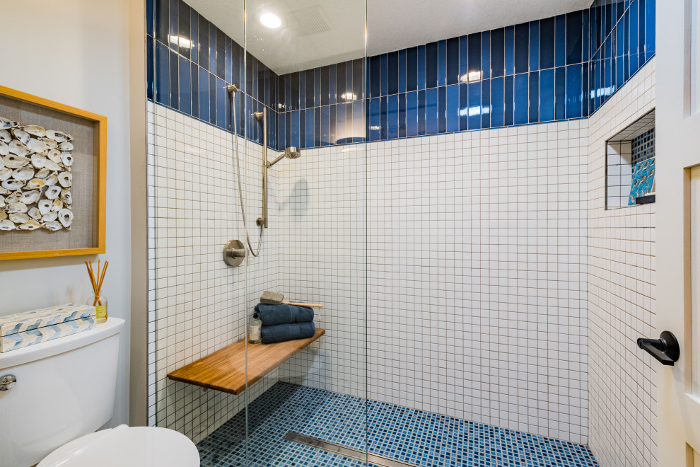 This is an example of a mid-sized transitional master bathroom in Minneapolis with shaker cabinets, white cabinets, an alcove tub, a curbless shower, a one-piece toilet, blue tile, porcelain tile, grey walls, porcelain floors, an undermount sink, quartzite benchtops, multi-coloured floor, an open shower, white benchtops, a shower seat, a double vanity and a built-in vanity.