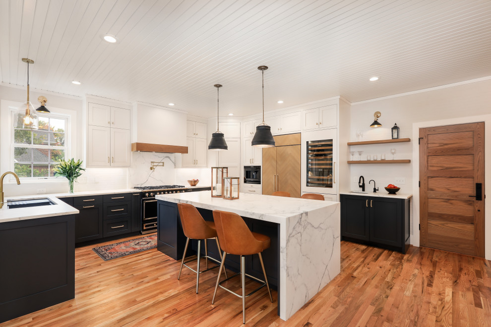 Open concept kitchen - transitional u-shaped medium tone wood floor and brown floor open concept kitchen idea with an undermount sink, shaker cabinets, black cabinets, white backsplash, paneled appliances, an island and multicolored countertops