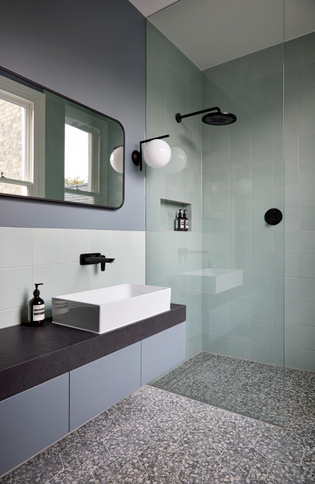 Пример оригинального дизайна: большая ванная комната в современном стиле с плоскими фасадами, синими фасадами, душевой комнатой, инсталляцией, зеленой плиткой, керамической плиткой, синими стенами, полом из керамической плитки, столешницей из гранита, разноцветным полом, открытым душем, черной столешницей, нишей, тумбой под две раковины и подвесной тумбой