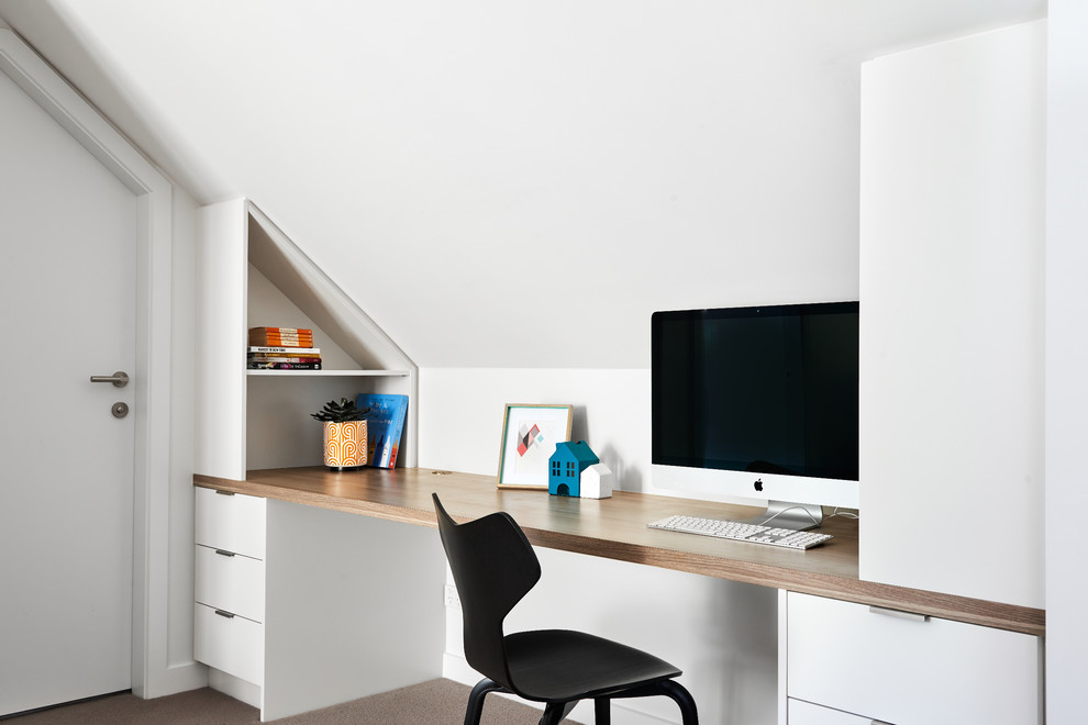 Photo of a contemporary home office in Sydney with white walls, carpet, a built-in desk and brown floor.
