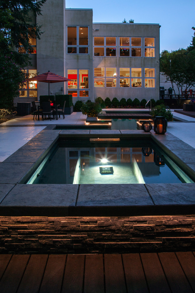 Photo of a mid-sized backyard l-shaped lap pool in Chicago with a hot tub and natural stone pavers.