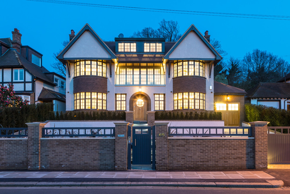 This is an example of a large arts and crafts three-storey beige house exterior in London with a hip roof.