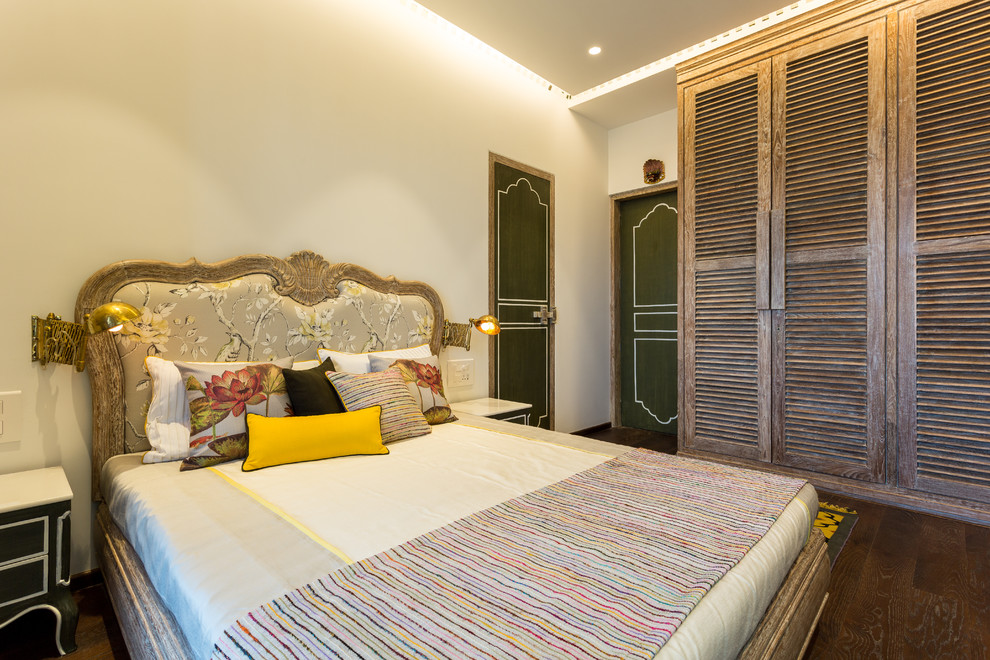 Photo of a traditional bedroom in Mumbai with white walls and medium hardwood floors.