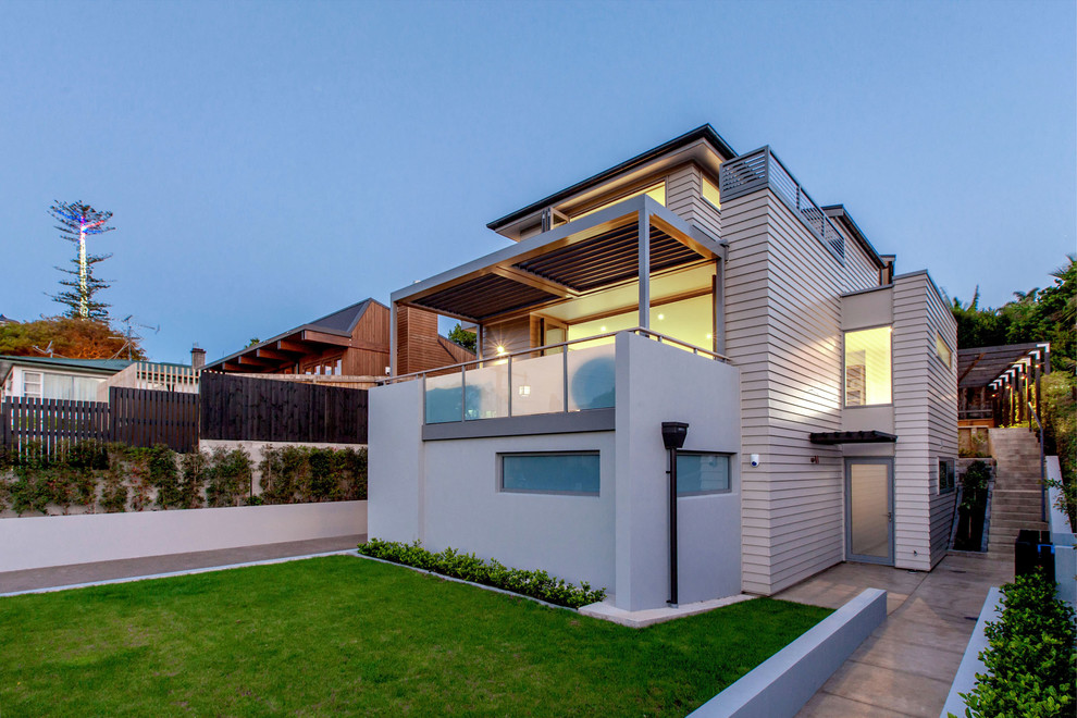 Design ideas for a large contemporary three-storey white exterior in Auckland with wood siding and a gable roof.
