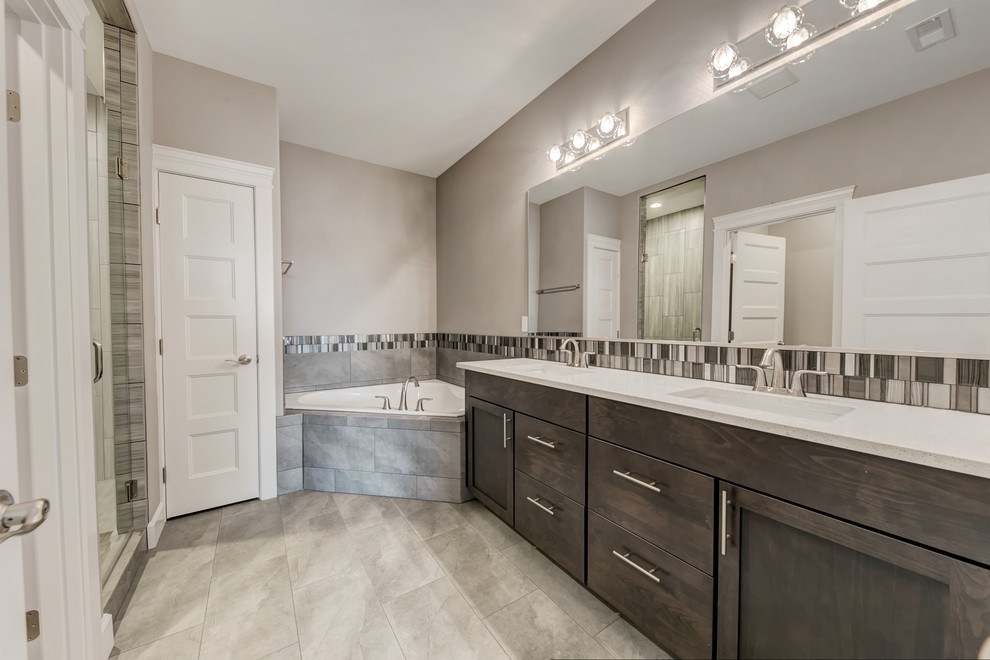 Mid-sized transitional master bathroom in Seattle with shaker cabinets, medium wood cabinets, a corner tub, an alcove shower, a two-piece toilet, gray tile, glass tile, grey walls, porcelain floors, an undermount sink, granite benchtops, grey floor and a hinged shower door.