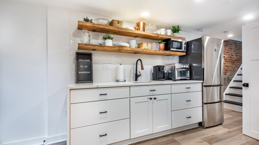 Medium sized traditional single-wall wet bar in DC Metro with a submerged sink, shaker cabinets, white cabinets, granite worktops, vinyl flooring, beige floors and feature lighting.