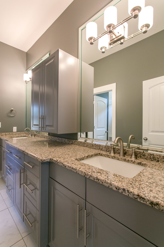 Photo of a traditional bathroom in Nashville with an undermount sink, raised-panel cabinets, grey cabinets, granite benchtops, a drop-in tub, a shower/bathtub combo, a two-piece toilet, grey walls, ceramic floors, white tile and ceramic tile.
