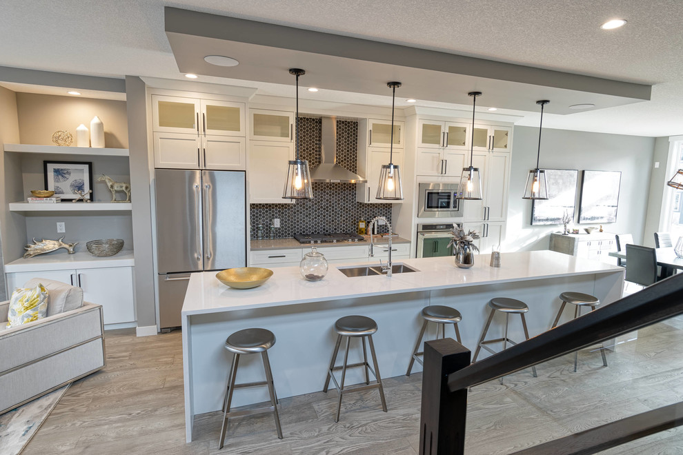 Example of a large transitional u-shaped vinyl floor and gray floor eat-in kitchen design with an undermount sink, recessed-panel cabinets, white cabinets, quartzite countertops, black backsplash, mosaic tile backsplash, stainless steel appliances, an island and white countertops