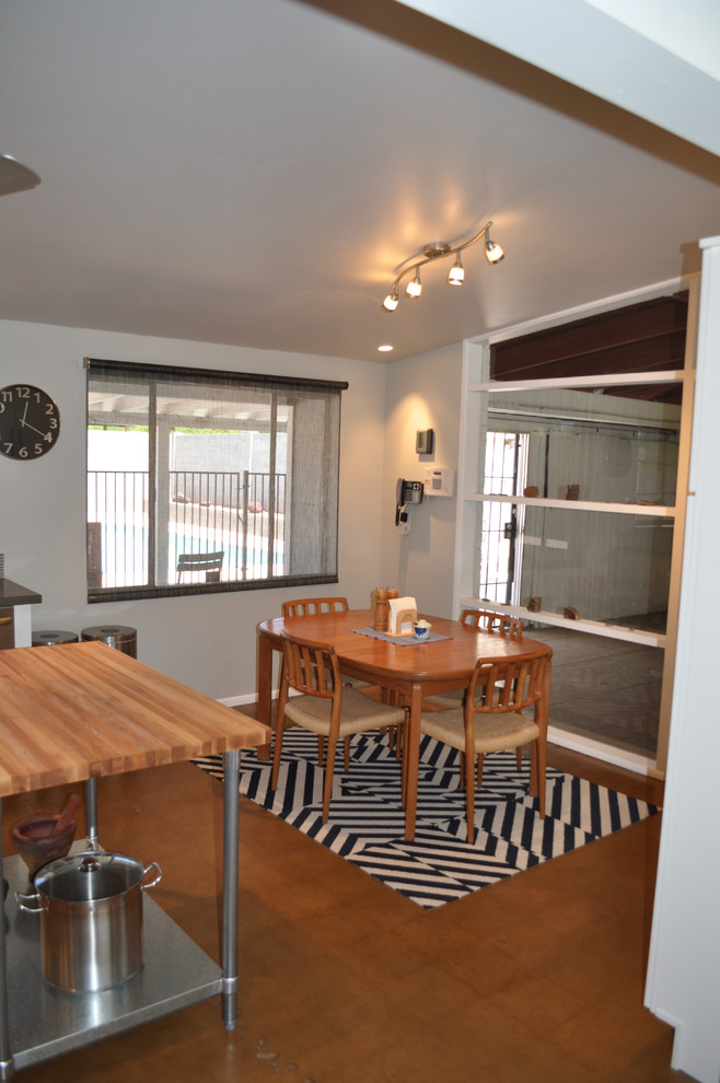 Example of a mid-sized 1950s l-shaped concrete floor eat-in kitchen design in Phoenix with an undermount sink, flat-panel cabinets, white cabinets, quartz countertops, gray backsplash, glass tile backsplash, stainless steel appliances and an island
