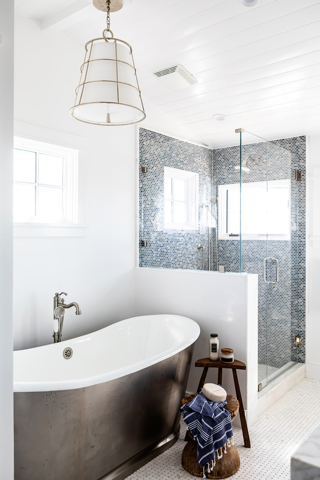 Example of a mid-sized beach style master black tile mosaic tile floor drop-in bathtub design in Sacramento with shaker cabinets, white cabinets, white walls, an undermount sink, quartz countertops and white countertops