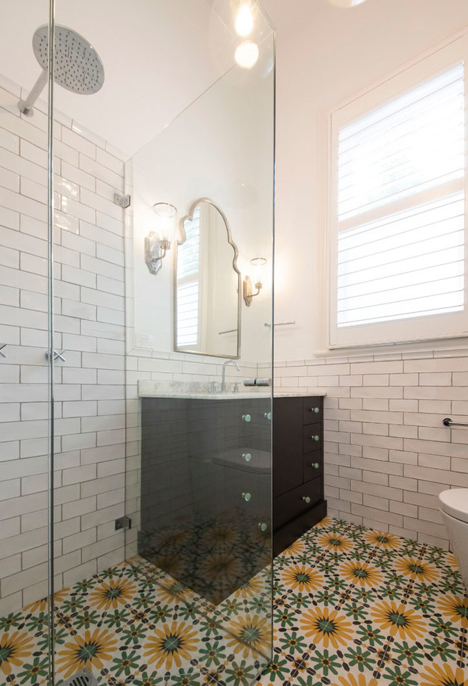 Стильный дизайн: большая ванная комната в средиземноморском стиле с плоскими фасадами, коричневыми фасадами, угловым душем, унитазом-моноблоком, белой плиткой, керамической плиткой, белыми стенами, полом из цементной плитки, душевой кабиной, врезной раковиной, мраморной столешницей, разноцветным полом, душем с распашными дверями и серой столешницей - последний тренд