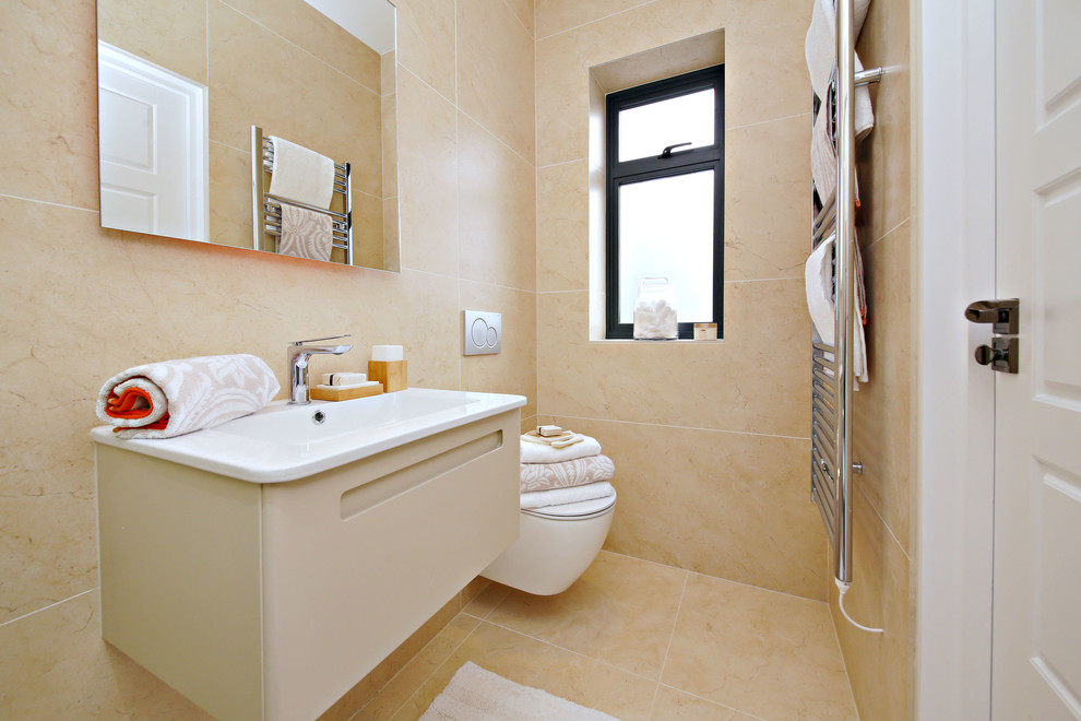 Inspiration for a mid-sized modern master bathroom in Hertfordshire with flat-panel cabinets, beige cabinets, an open shower, a wall-mount toilet, beige tile, porcelain tile, beige walls, porcelain floors, a wall-mount sink, solid surface benchtops, beige floor, a sliding shower screen and white benchtops.