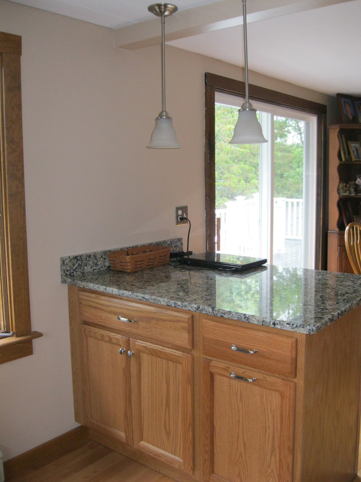 Inspiration for a mid-sized transitional l-shaped light wood floor kitchen remodel in Boston with a peninsula, flat-panel cabinets, light wood cabinets, granite countertops, stainless steel appliances and an undermount sink