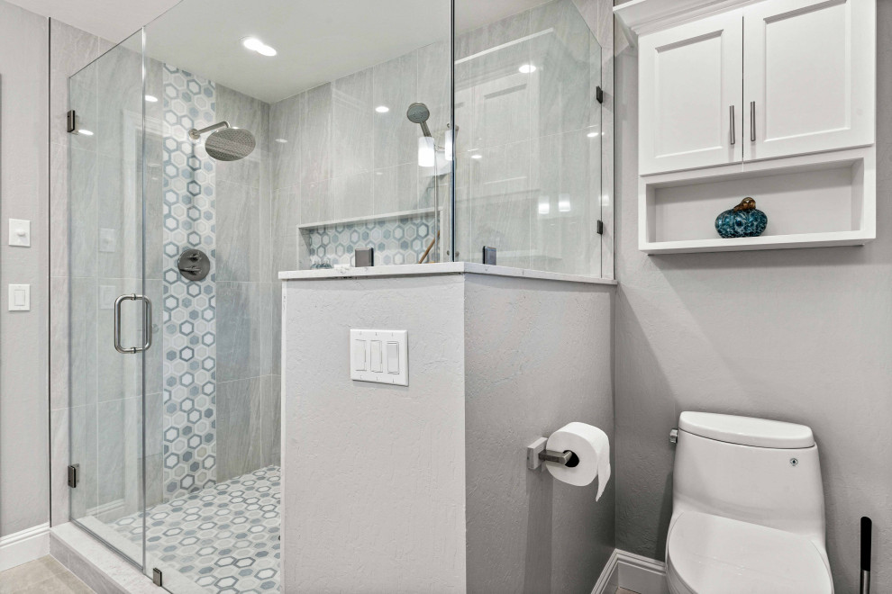 Foto på ett mellanstort eklektiskt vit en-suite badrum, med luckor med infälld panel, vita skåp, en dubbeldusch, en toalettstol med separat cisternkåpa, grå kakel, porslinskakel, grå väggar, klinkergolv i porslin, ett undermonterad handfat, bänkskiva i kvarts, grått golv och dusch med gångjärnsdörr