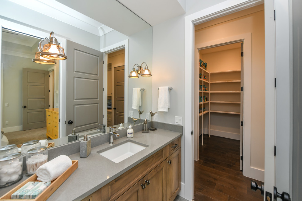 This is an example of a mid-sized transitional kids bathroom in Tampa with recessed-panel cabinets, light wood cabinets, grey walls, medium hardwood floors, an undermount sink and brown floor.