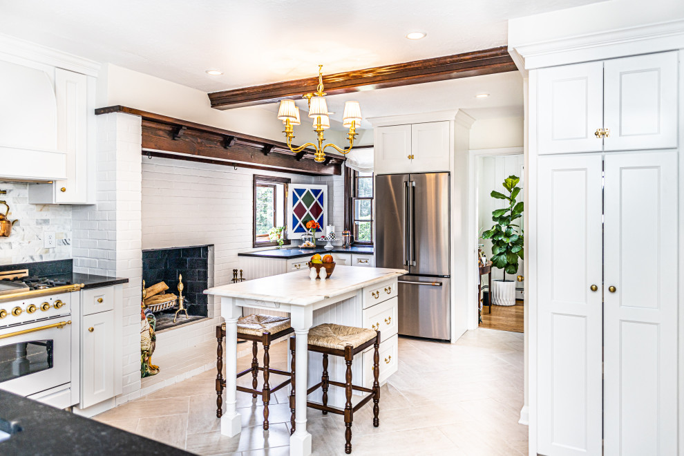 Small l-shaped kitchen pantry in Baltimore with an undermount sink, shaker cabinets, white cabinets, marble benchtops, white splashback, marble splashback, stainless steel appliances, porcelain floors, with island, beige floor, black benchtop and exposed beam.