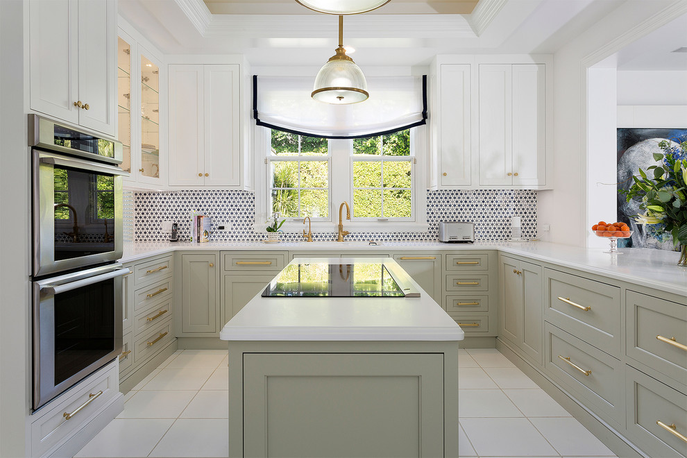 Mid-sized transitional l-shaped ceramic tile and beige floor open concept kitchen photo in Miami with an undermount sink, recessed-panel cabinets, white cabinets, solid surface countertops, multicolored backsplash, mosaic tile backsplash, stainless steel appliances and an island