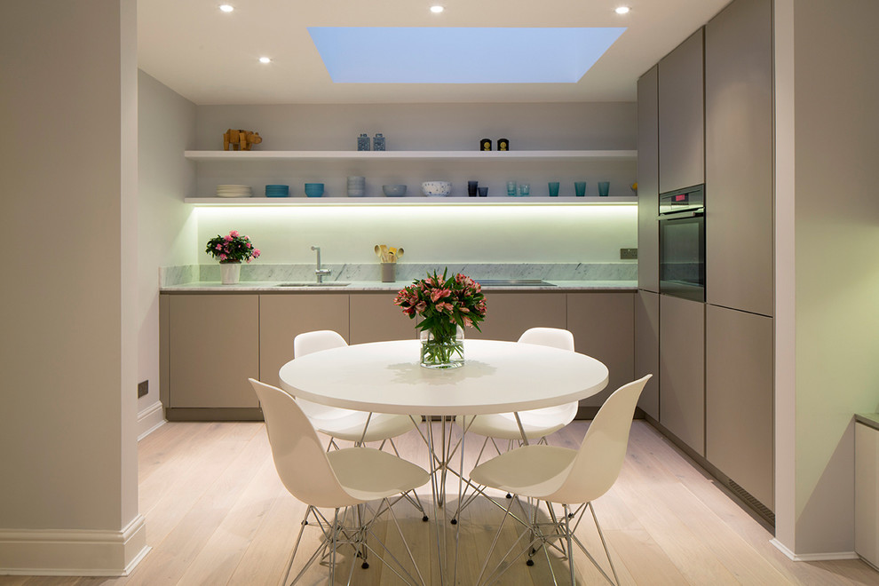 Photo of a contemporary eat-in kitchen in London with an undermount sink, flat-panel cabinets, grey cabinets, light hardwood floors and no island.